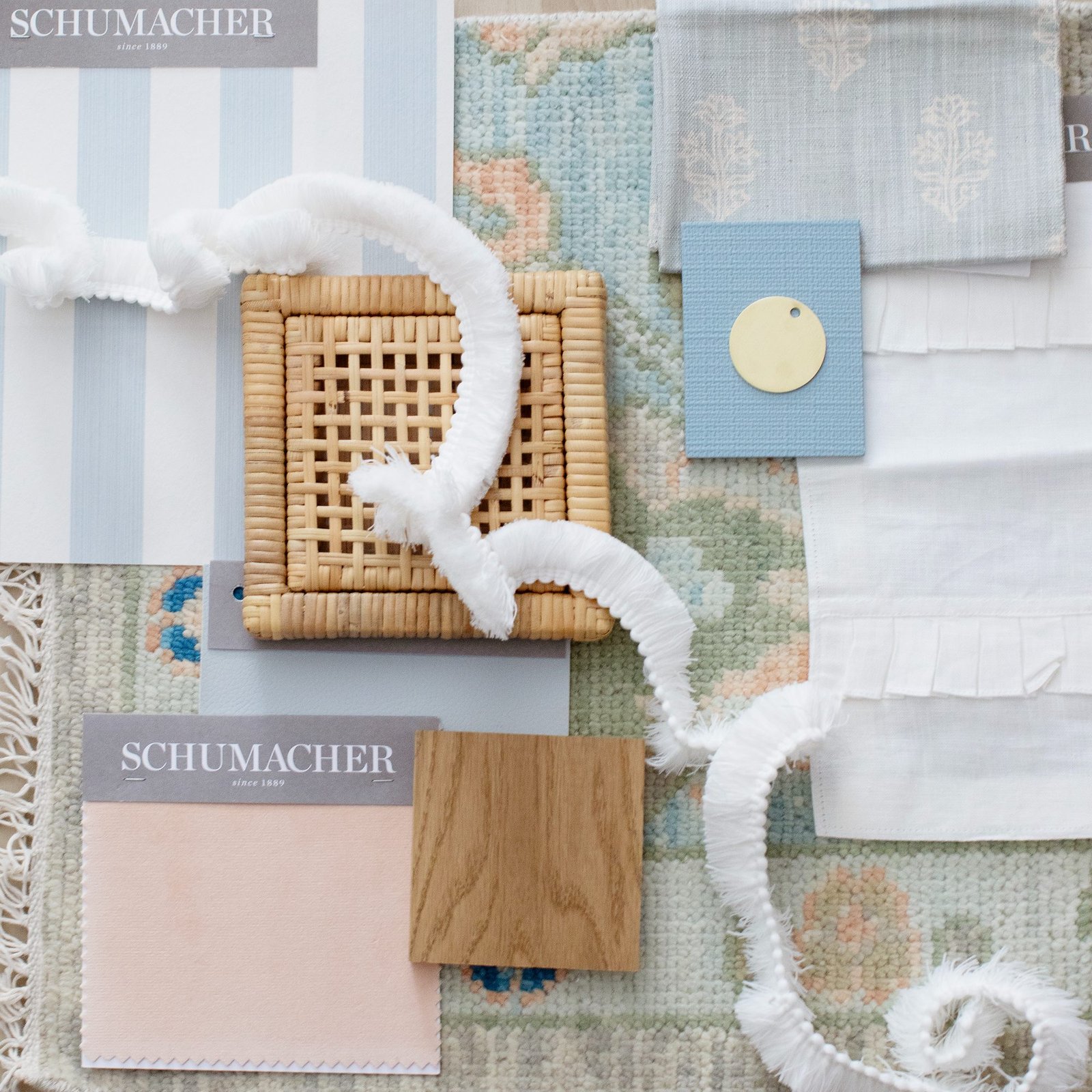Flat lay of a scheme in progress — dusty pink velvet, white oak, cane, block-print linens, and fringed trim