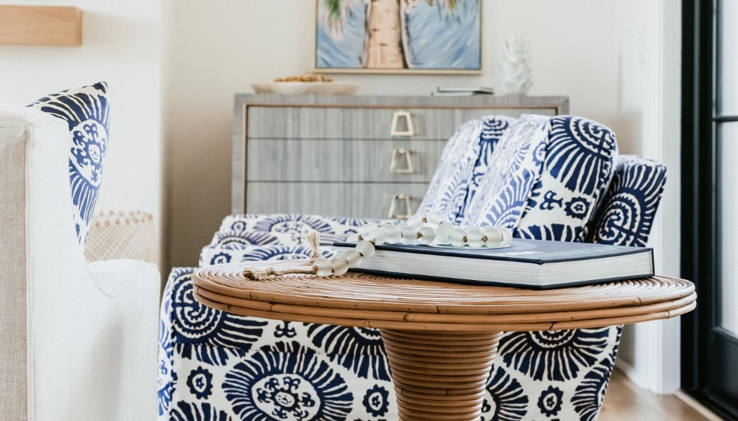 Rattan side table and blue-and-white patterned armchair in a sunlit sitting area