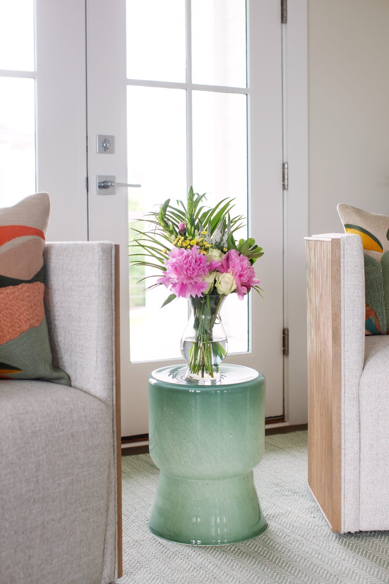 Blue and white hydrangeas in a footed glass vase beside cane-wrapped candles and coastal design books