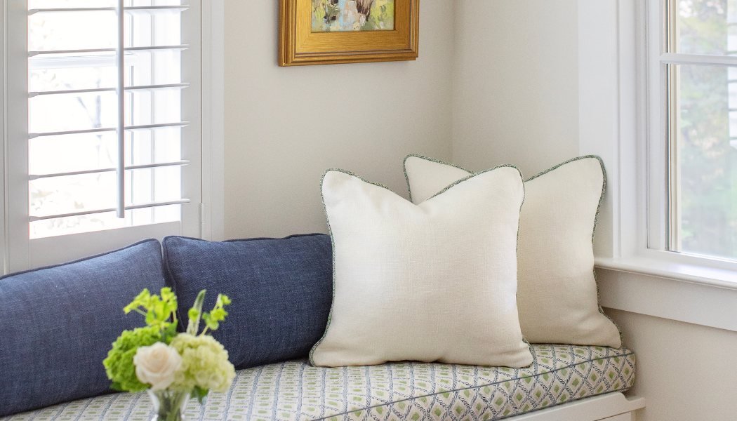 Window-seat nook with green trellis cushion, linen pillows and plantation shutters