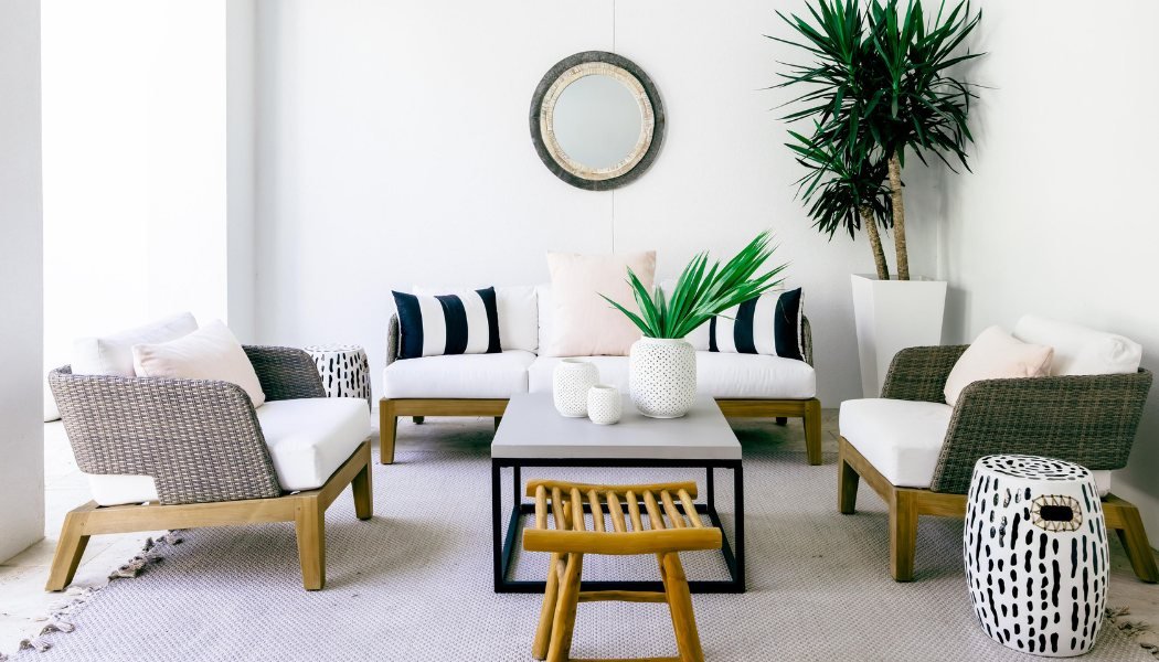 Bright covered patio with woven lounge chairs, striped pillows and a concrete table