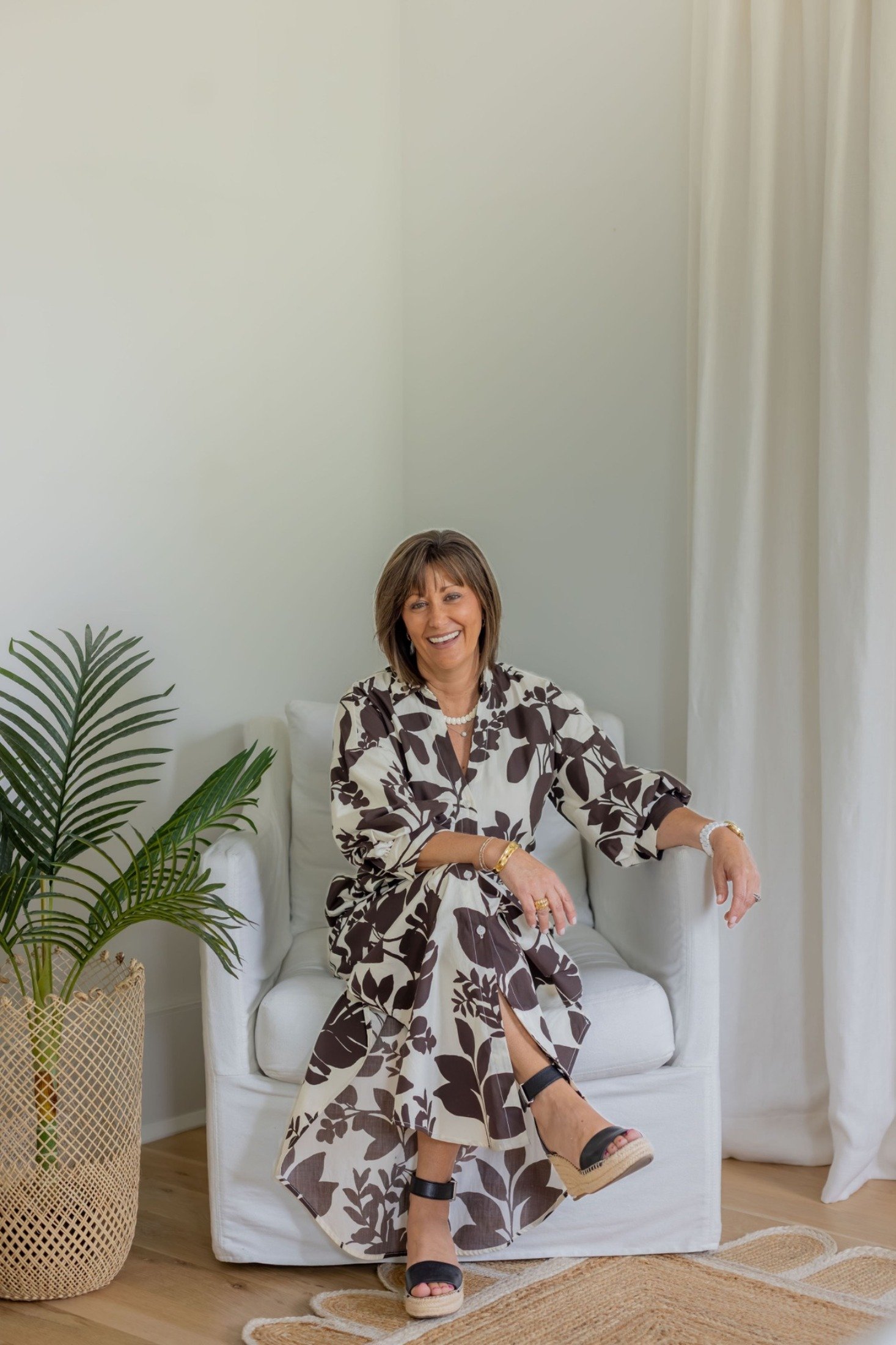 Andrea Dussault, Founder & Principal Designer, seated in a white slipcovered chair