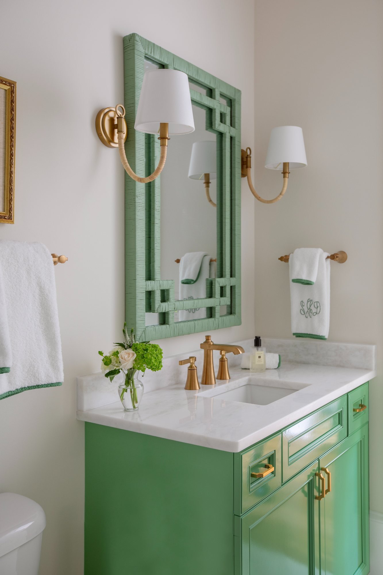 Powder room with grass-green lacquer vanity, fretwork mirror, and brass sconces