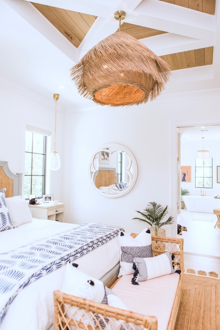 Primary bedroom with grass pendant, coffered ceiling, and rattan bench