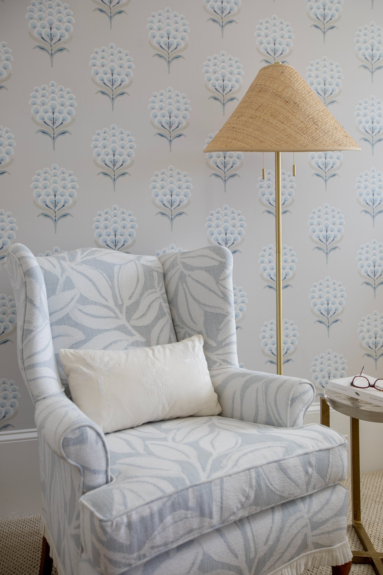Skirted wing chair and brass floor lamp with raffia shade against block-print paper