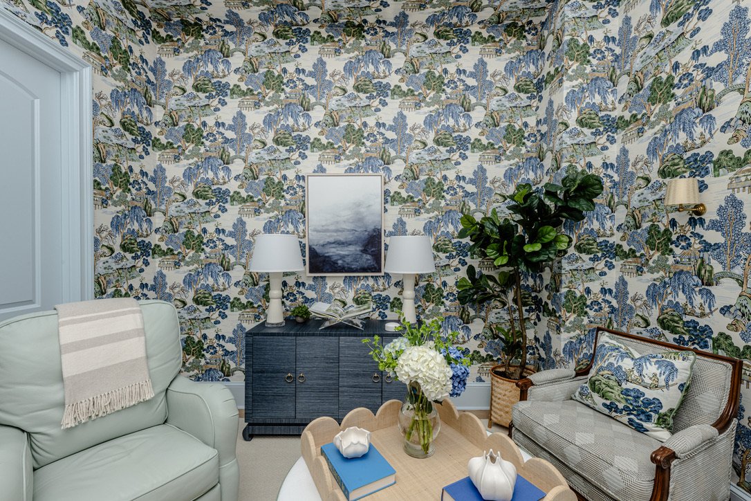 Sitting room papered in blue-and-green chinoiserie with mint leather chair and navy console