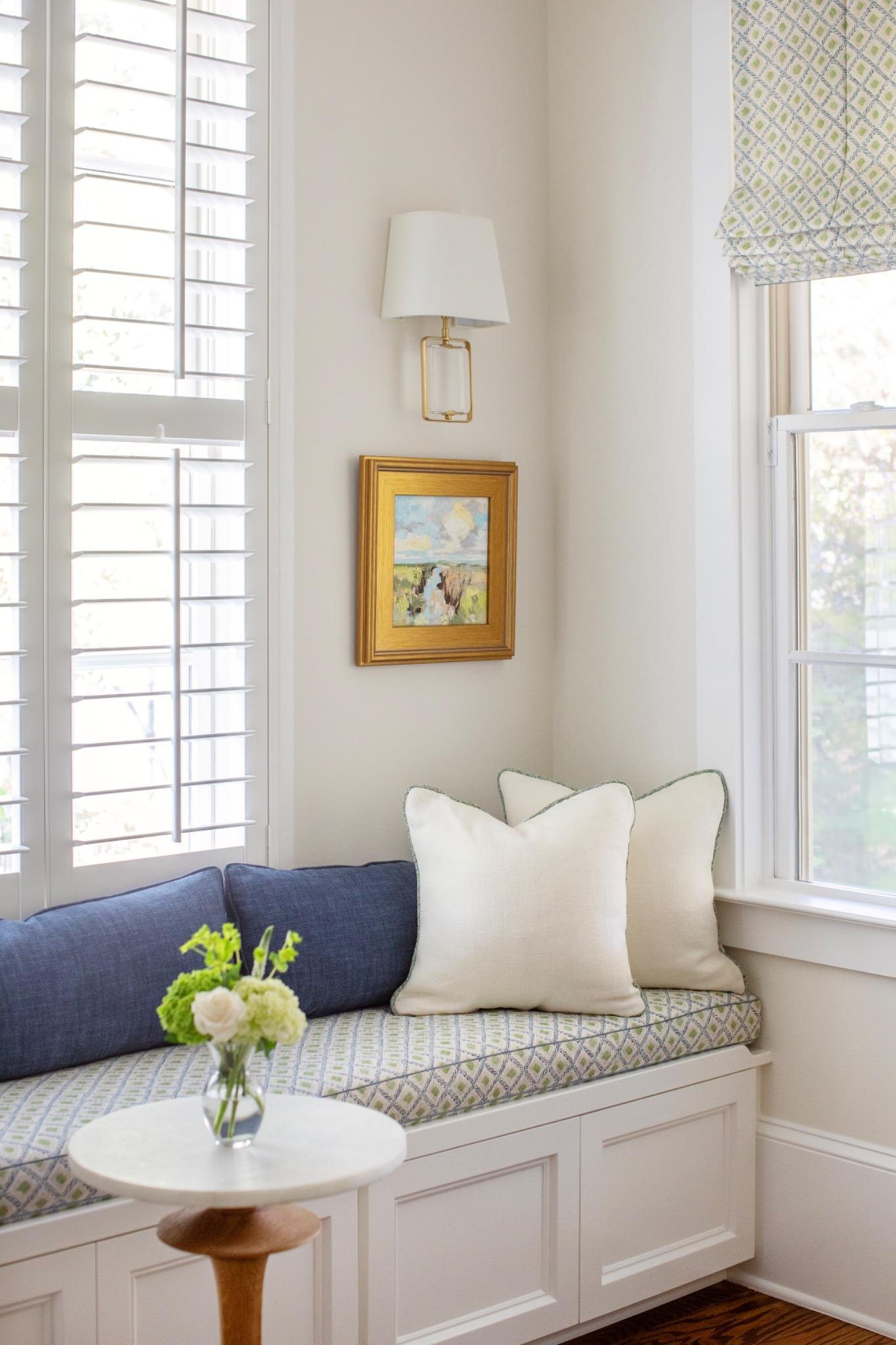 Breakfast nook with built-in banquette, green diamond-print cushion, and brass sconce