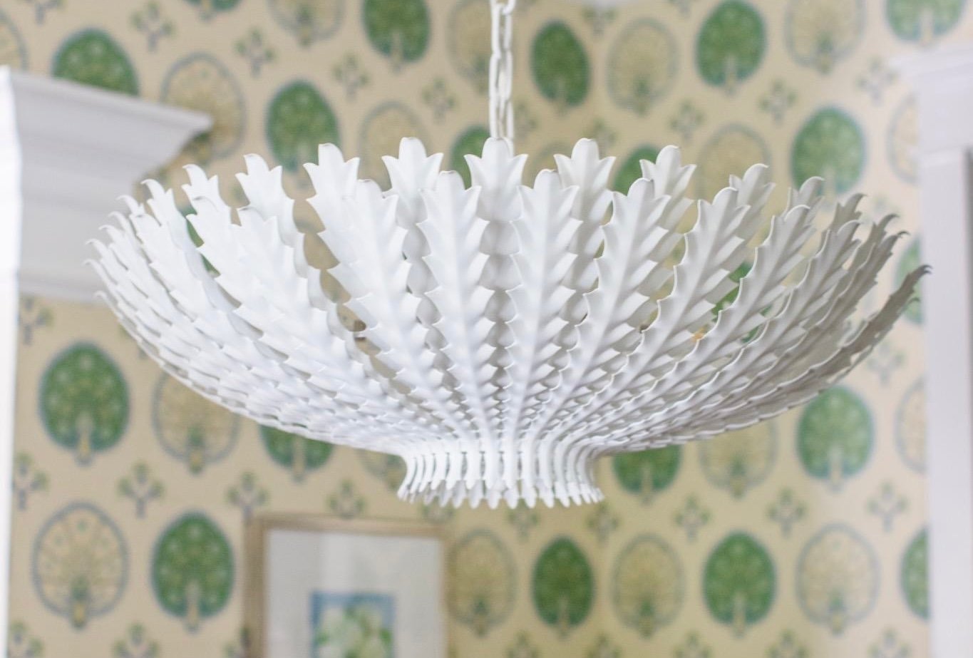 White tole palm-frond chandelier against green medallion wallpaper