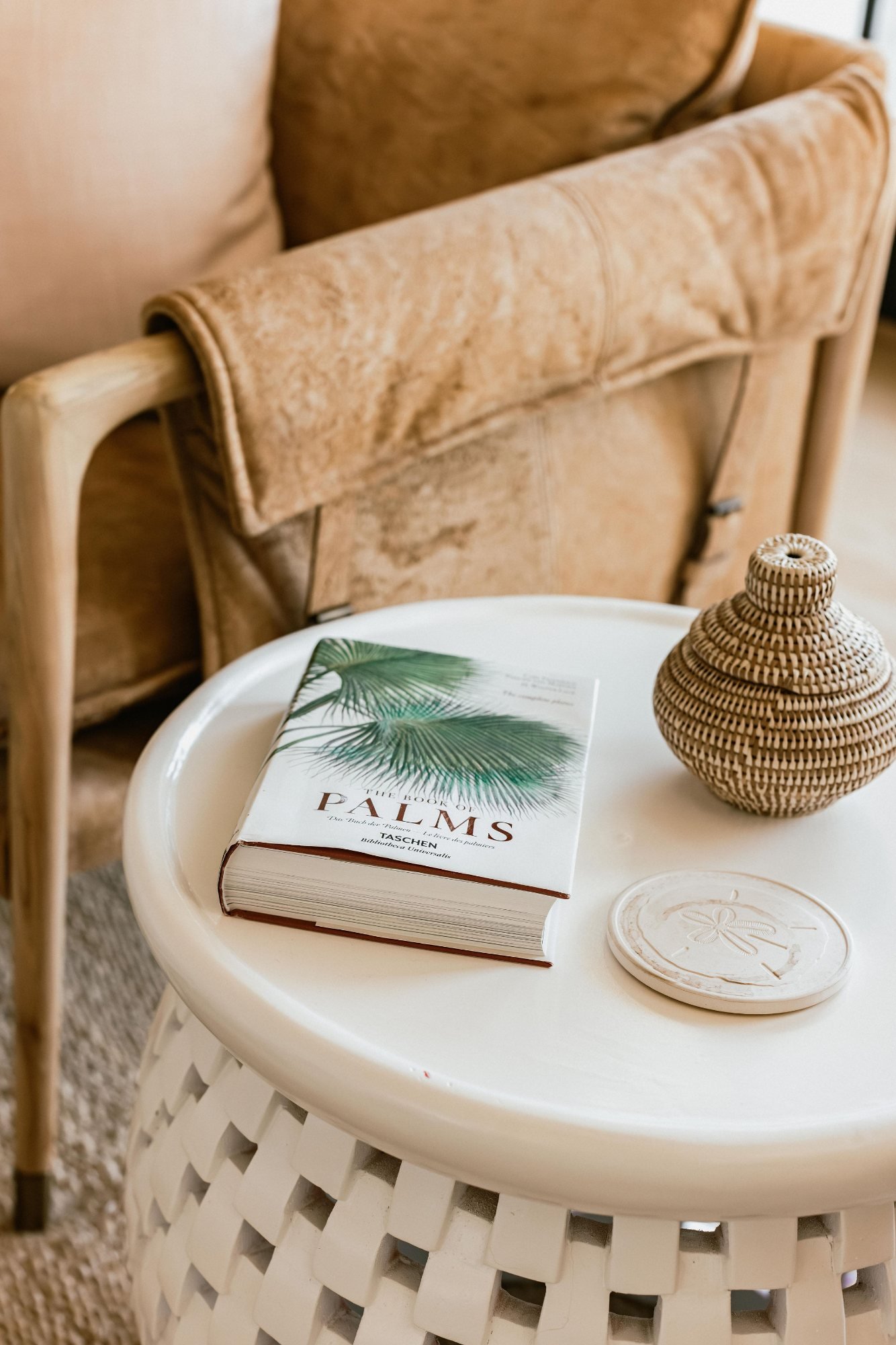 Side table styled with a book and rattan vessel beside the lounge chair