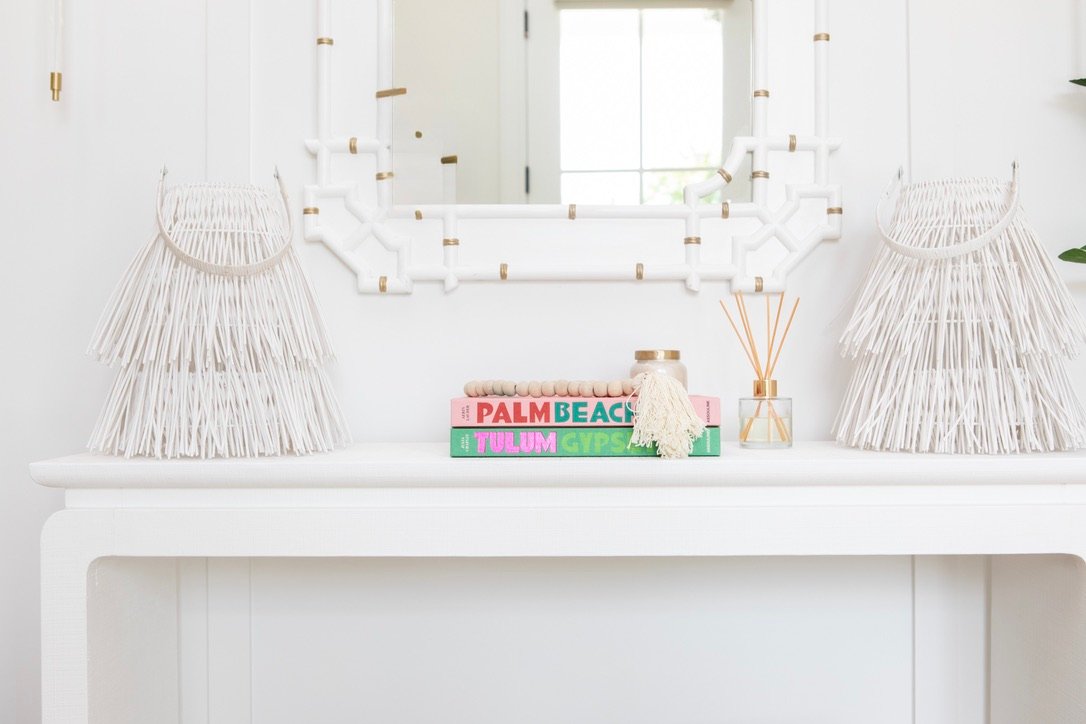 Console styled with white fringe wall hangings and stacked books