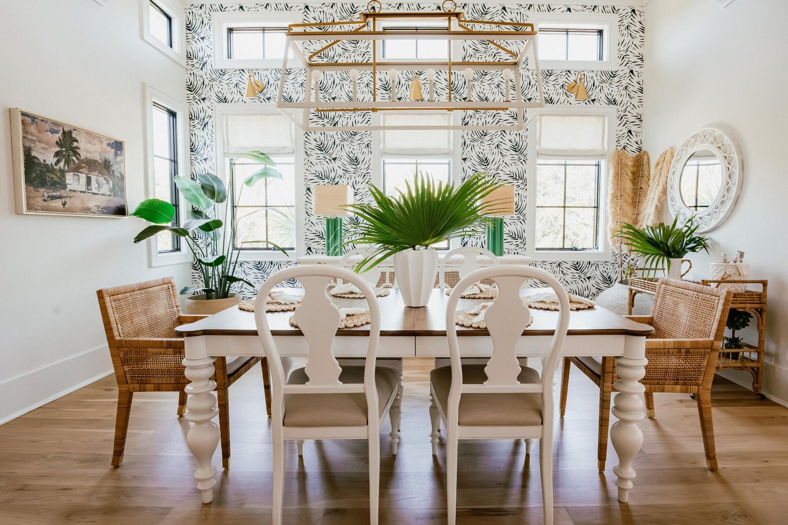 Dining room with palm-print wallpaper, lacquered table, and rattan chairs