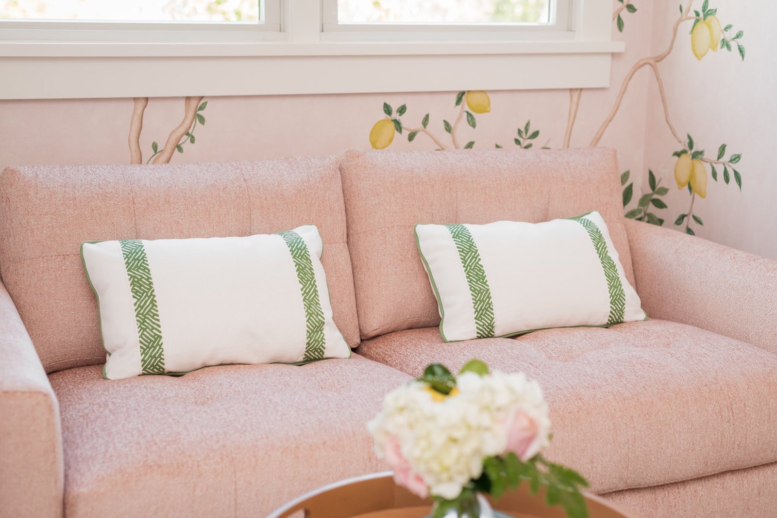 Blush bouclé loveseat with green-striped lumbar pillows
