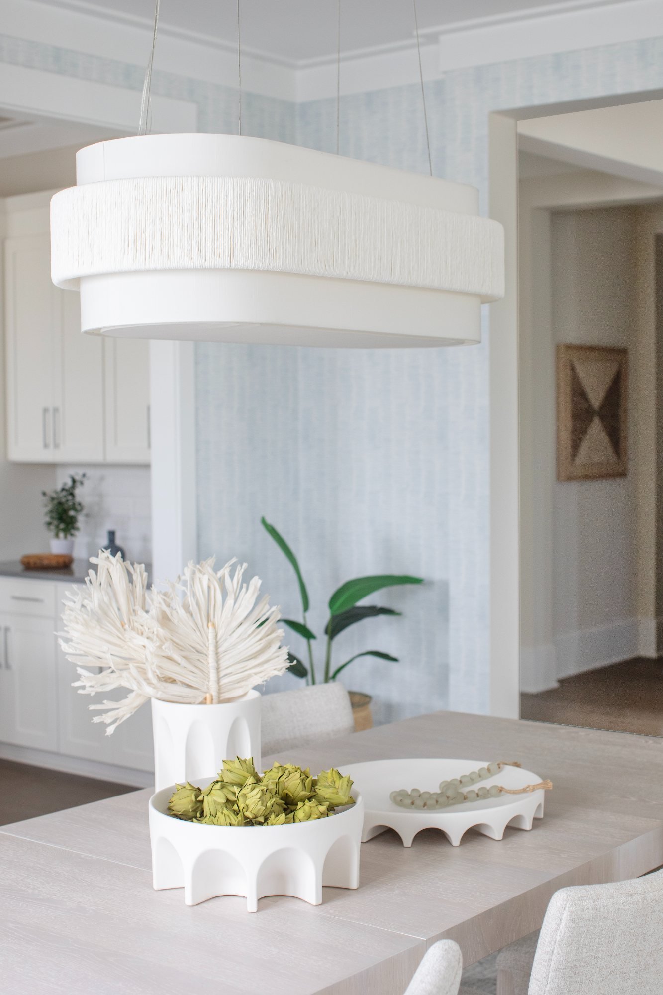 Arched ceramic bowls and dried artichokes centered under the fringed pendant