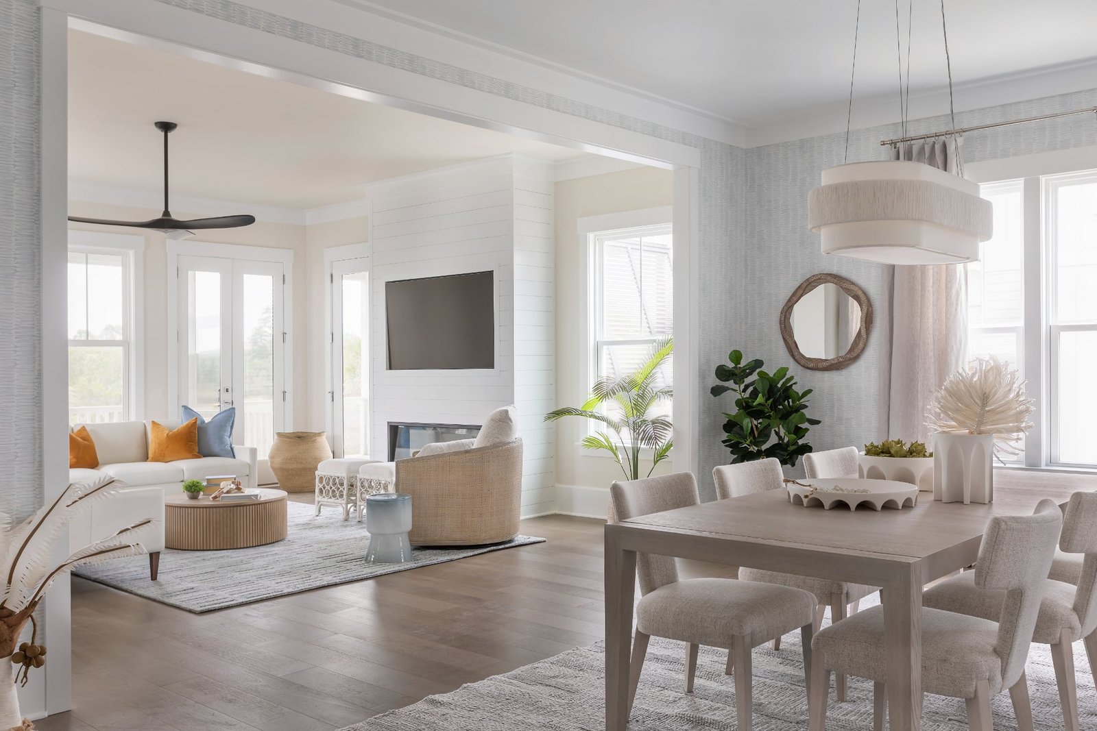 Dining room open to the living room with fringed pendant and shiplap fireplace beyond
