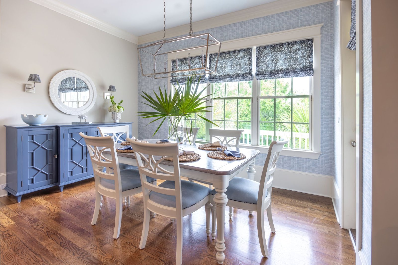 Dining room from the doorway with paired blue cabinets and oval mirror