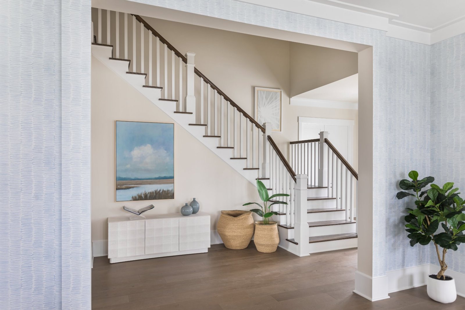 Entry with textured blue wallcovering, white console, and marsh landscape painting