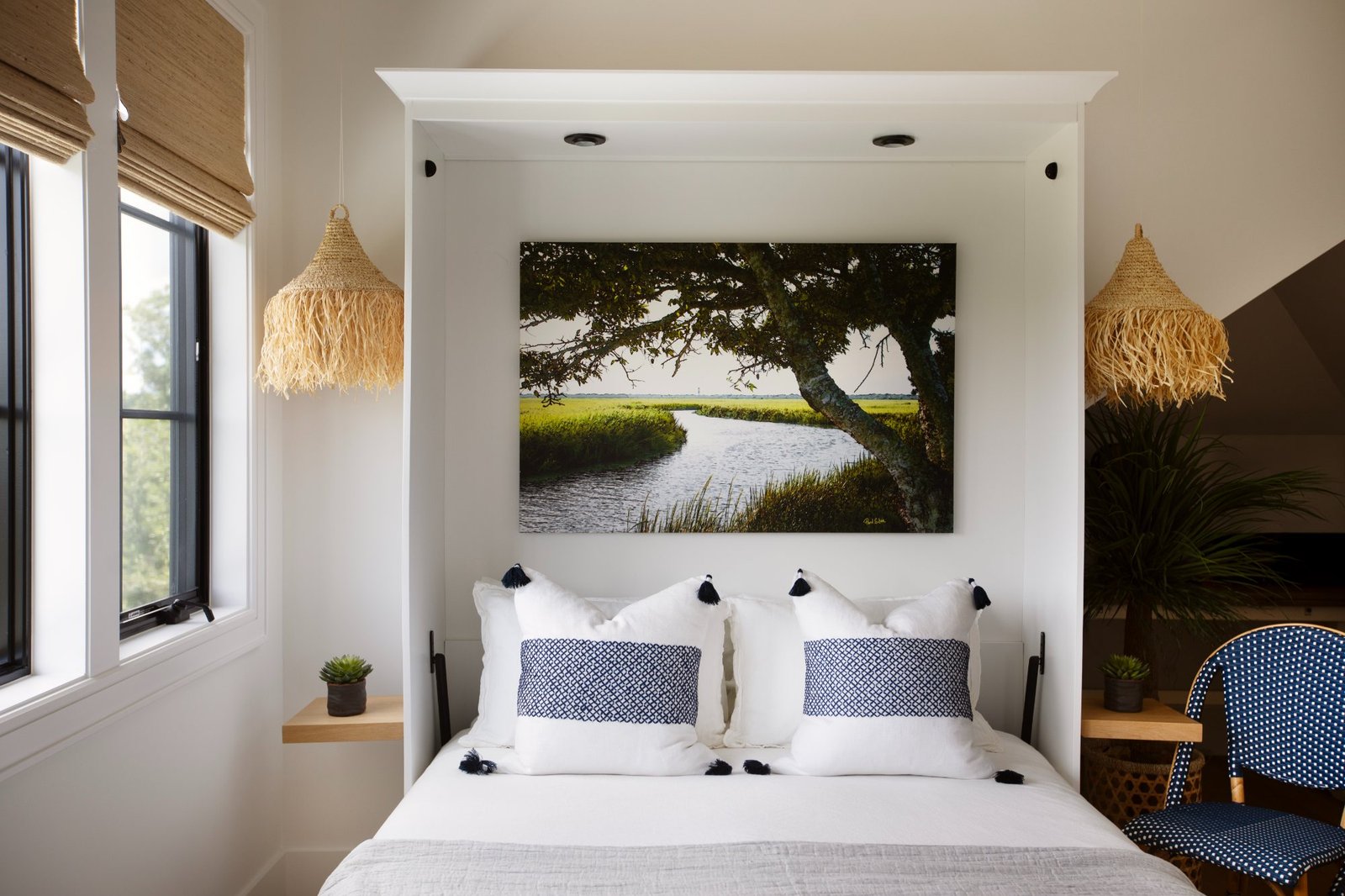 Guest room with marsh photograph, raffia pendants, and tasseled pillows
