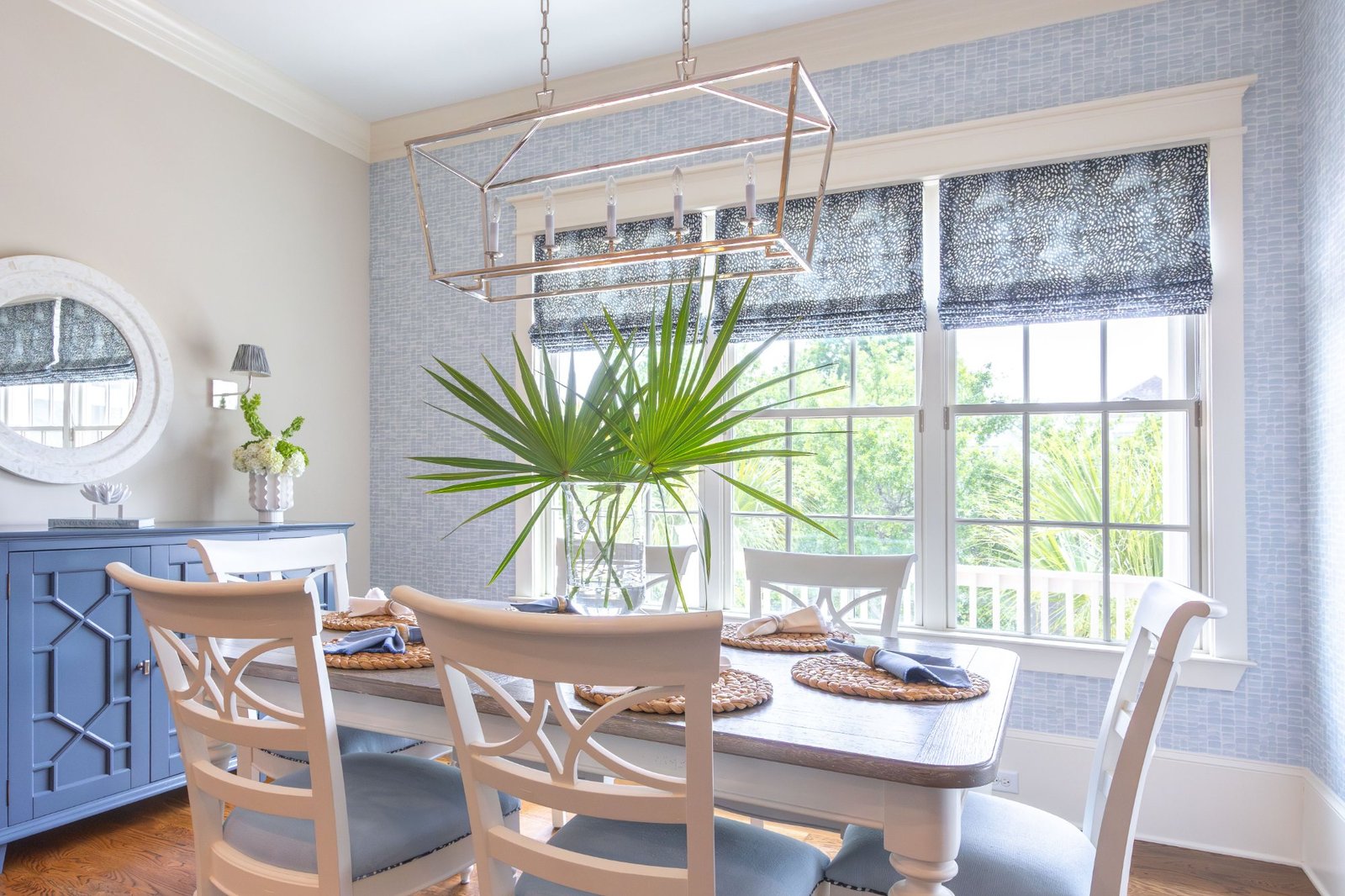 Dining room with blue grasscloth, nickel lantern, and patterned roman shades