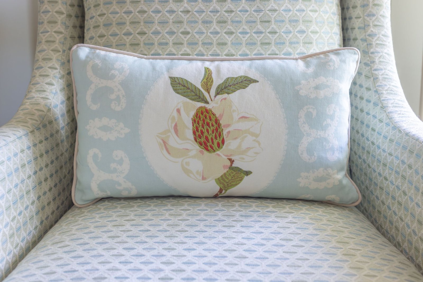 Close view of the magnolia lumbar pillow and its blush piping