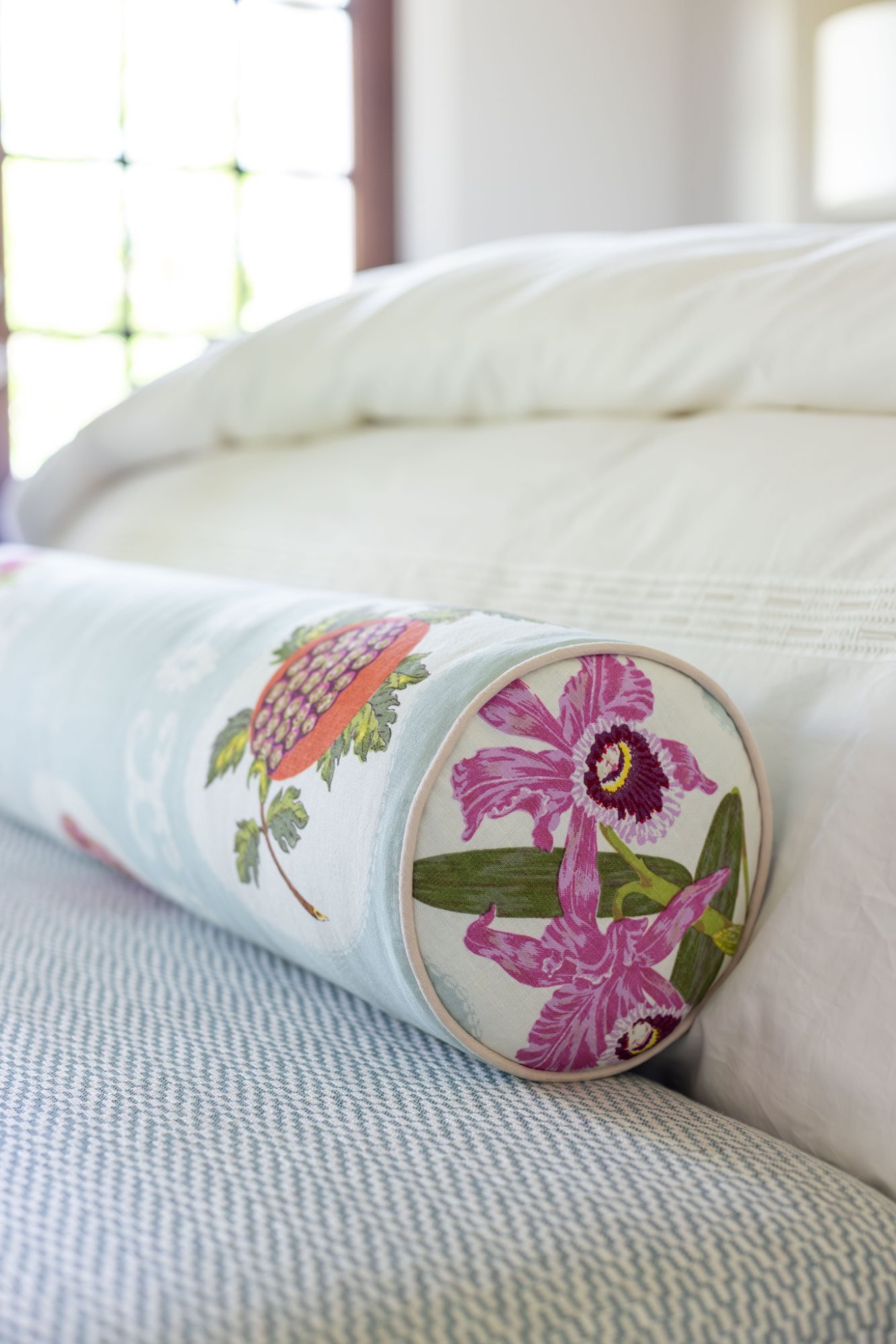Botanical print bolster with contrast piping across a white duvet