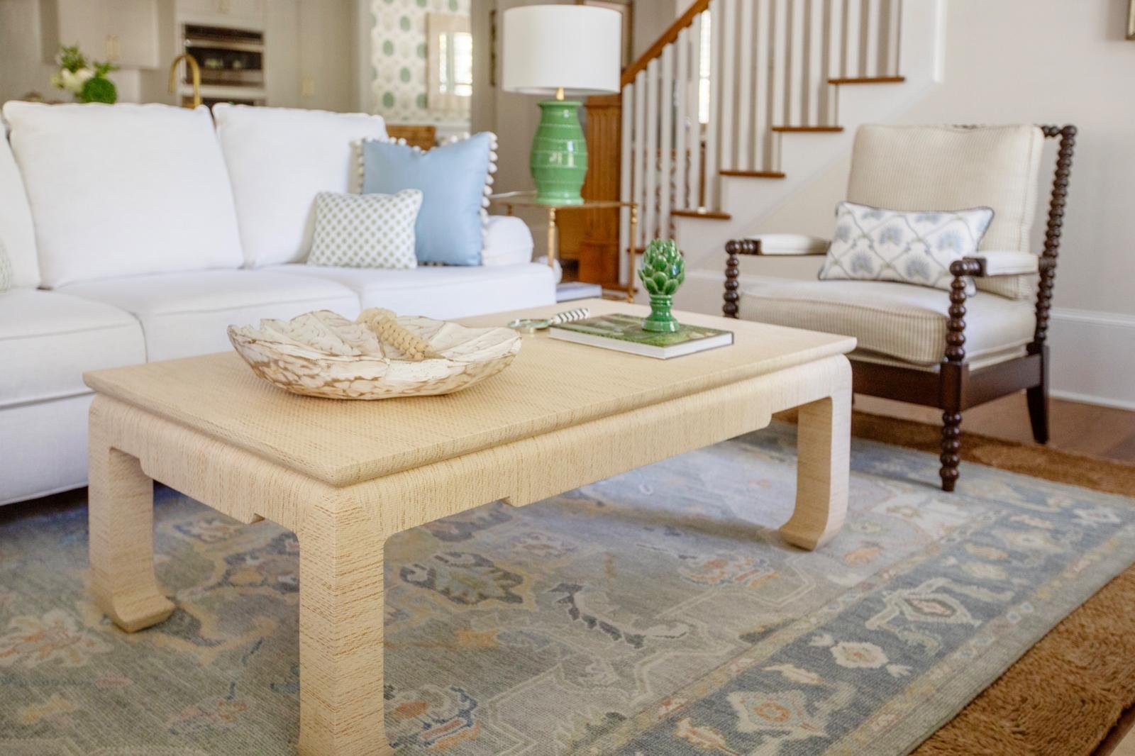 Raffia-wrapped coffee table with shell bowl on a faded blue Oushak rug