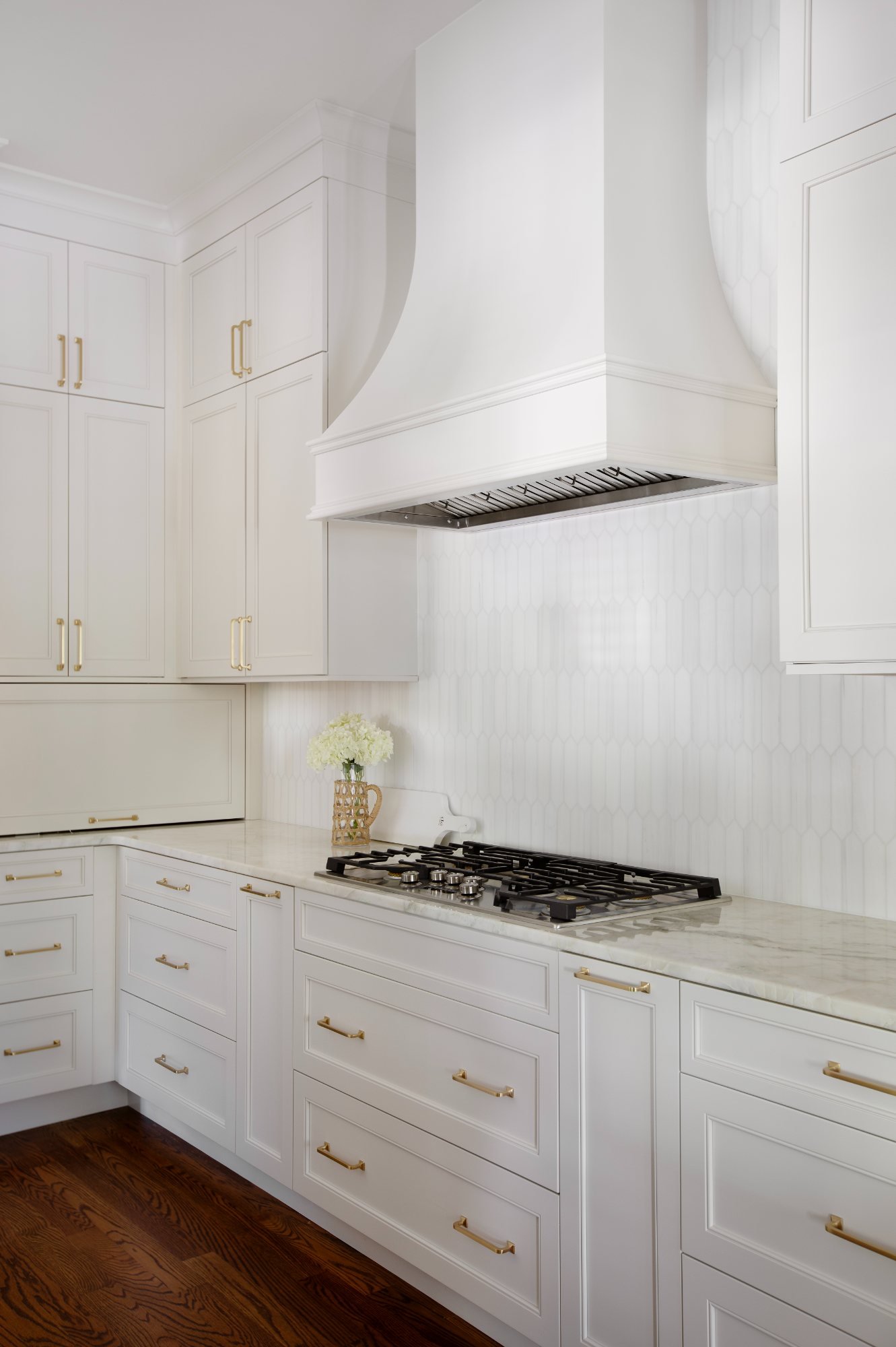 Plaster hood over the cooktop with picket tile backsplash and brass hardware