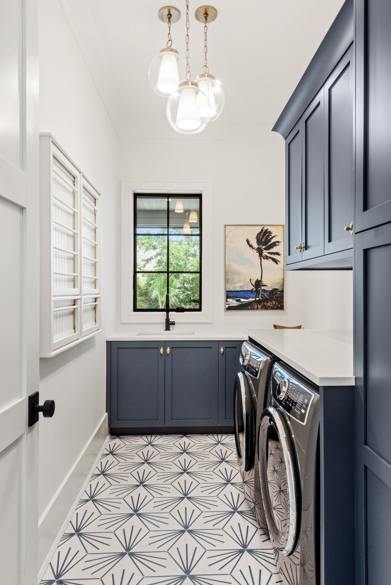 Laundry room with navy cabinetry and graphic starburst tile floor