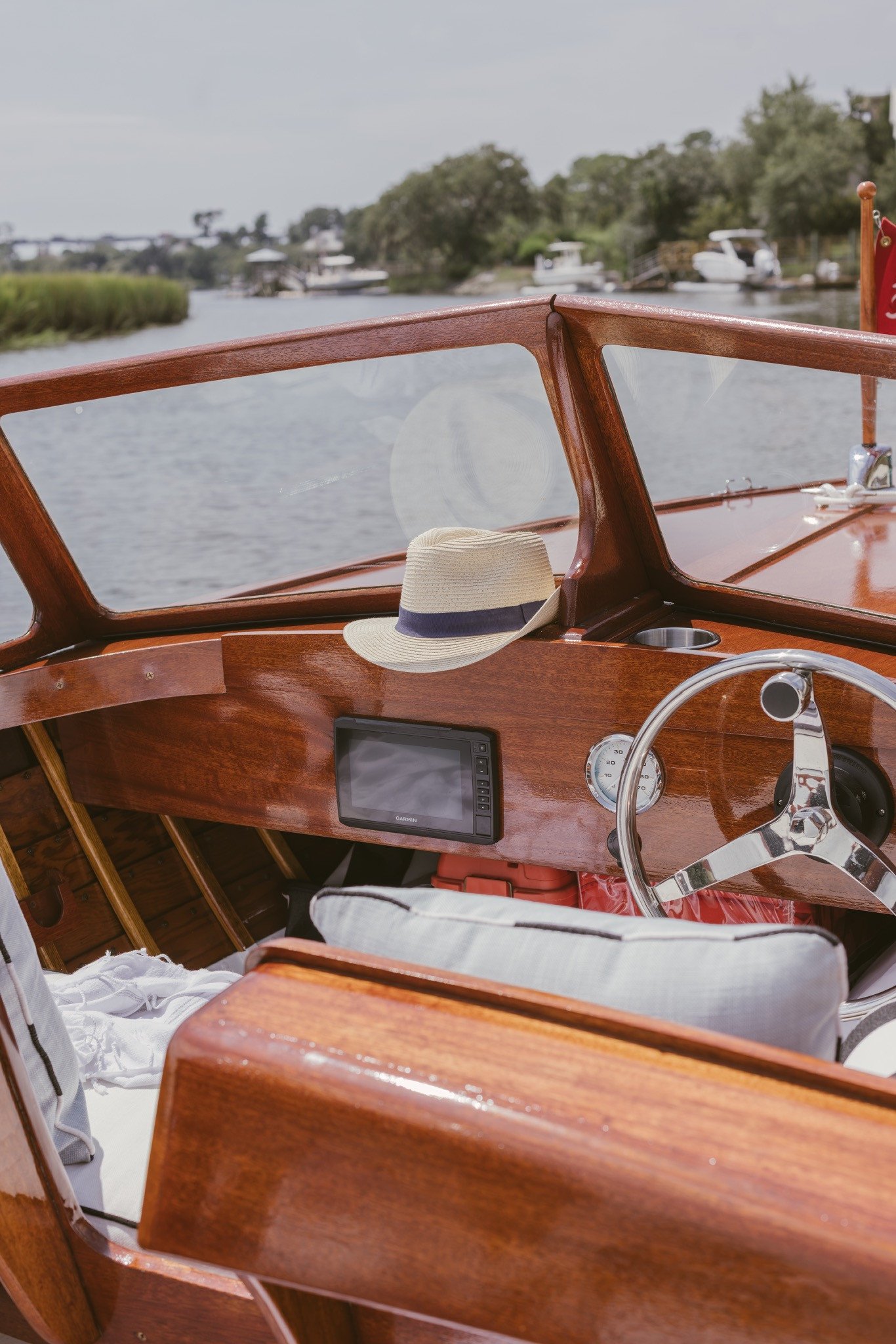 Straw hat resting on the mahogany dash beside the chrome wheel