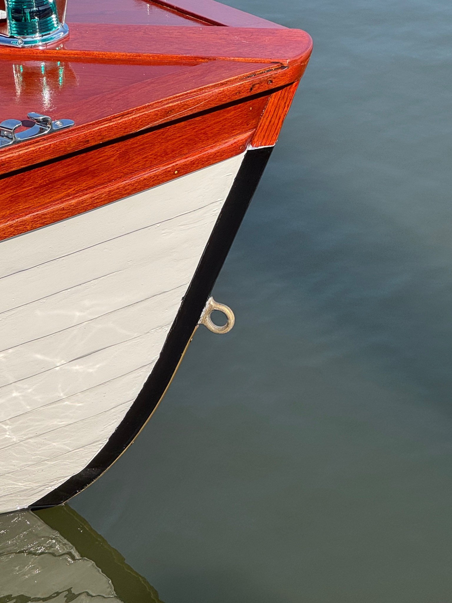Bow detail: varnished deck, white planking, and black waterline stripe