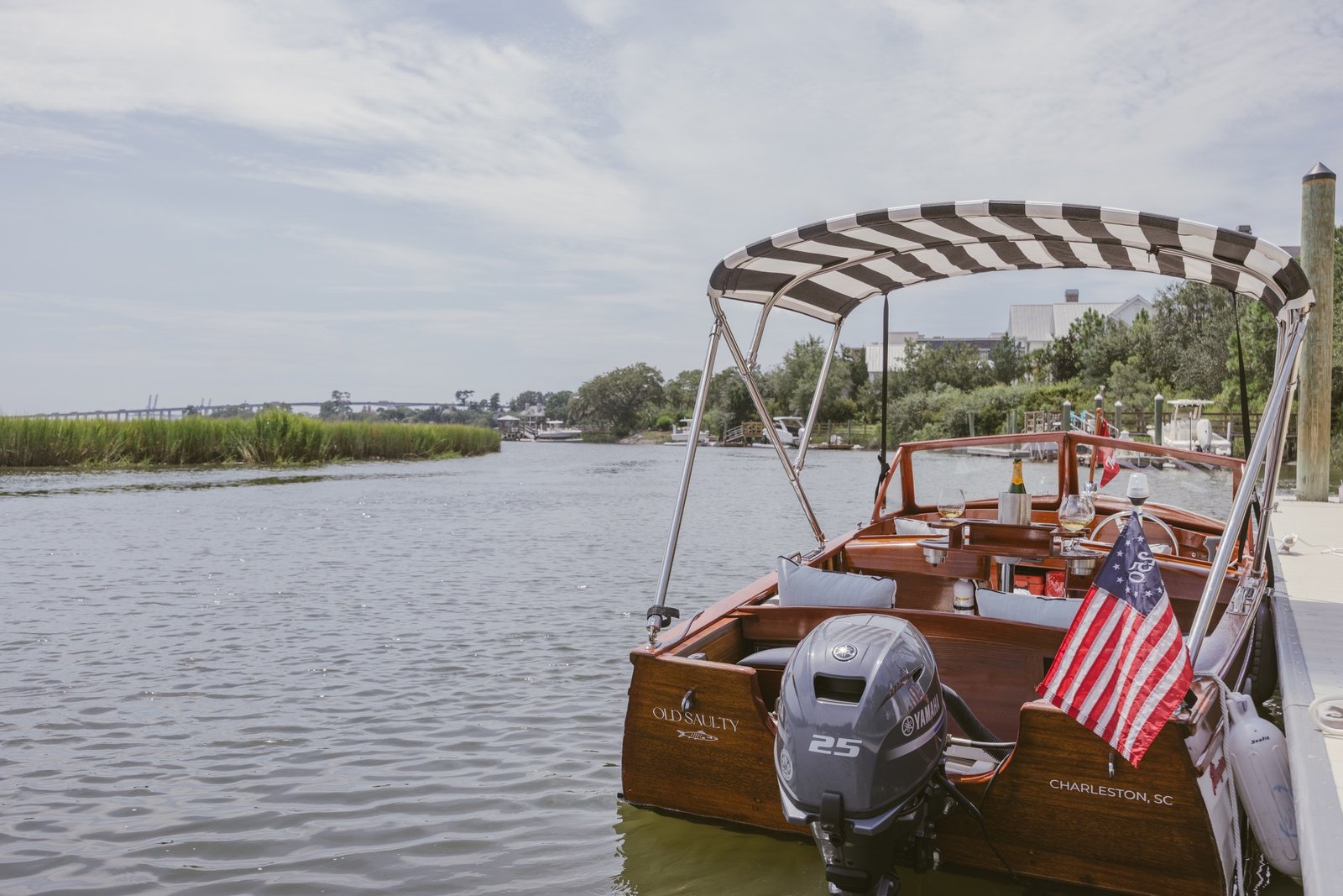 Old Saulty tied at the dock under her black-and-white striped bimini, marsh creek beyond