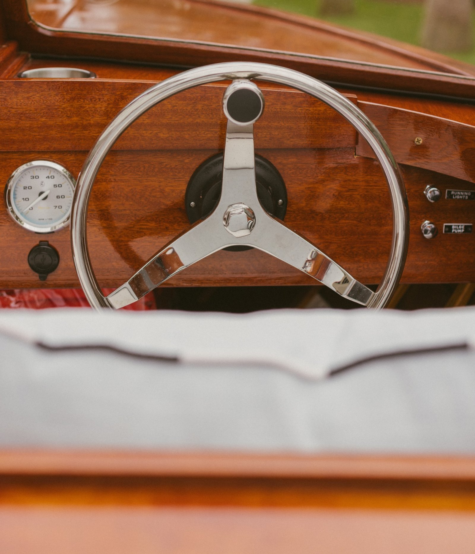 Chrome three-spoke wheel and tachometer on the mahogany dash