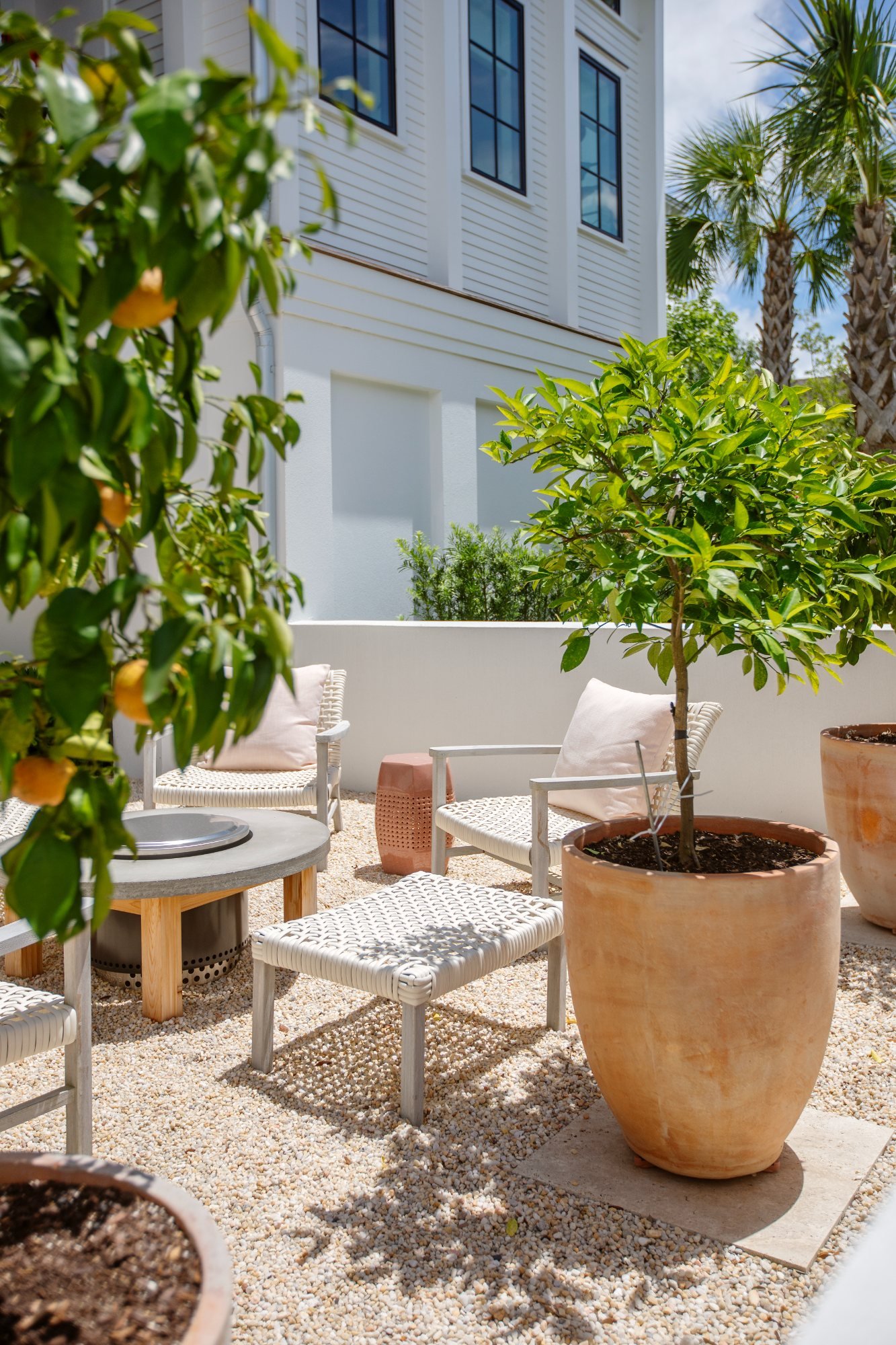 Gravel garden with citrus trees in terracotta pots and a fire table