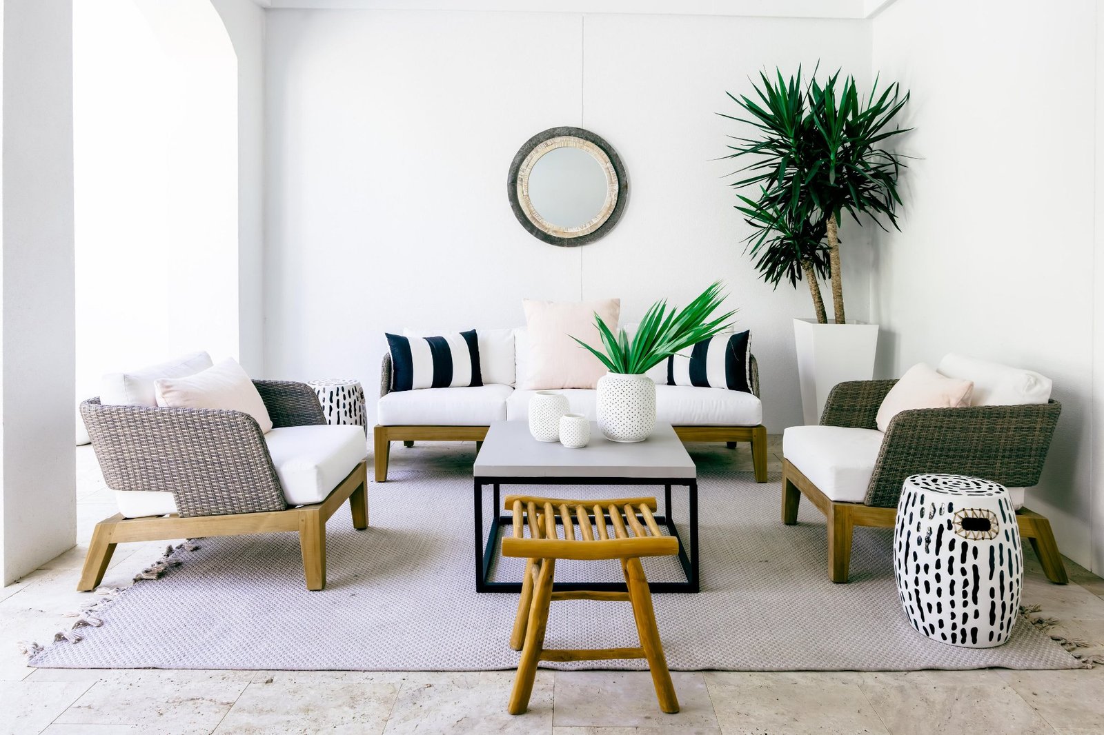 Covered outdoor room with woven lounge chairs and striped pillows
