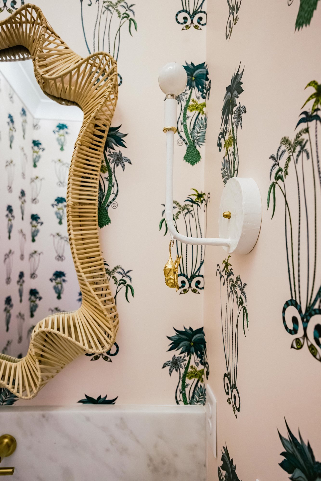 Wavy rattan mirror edge and white sconce with brass detail
