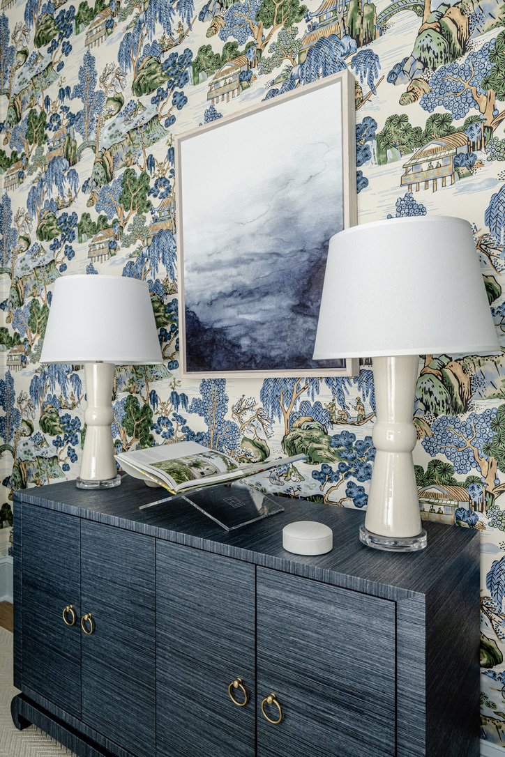 Navy grasscloth console styled with ivory lamps and an open book