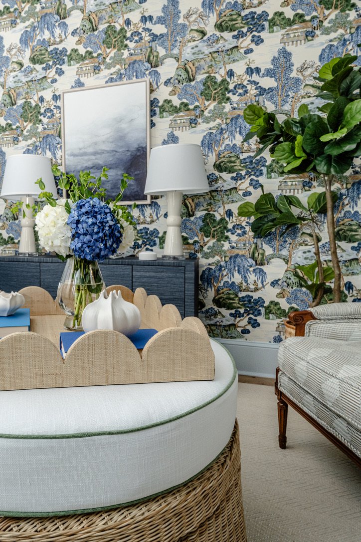 Hydrangeas and a scalloped tray on the round woven ottoman in front of the console
